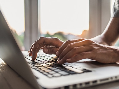 Hands typing on a laptop computer